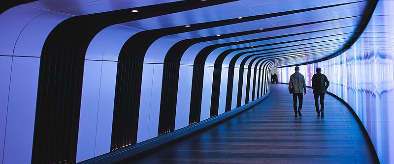 Two men walk down a corridor